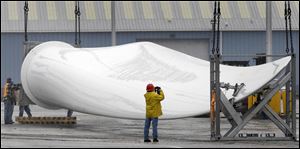 A worker takes a picture of one of three 165-foot-long blades from a giant wind turbine after it was unloaded from the deck of the ship Federal Pioneer at the Port of Cleveland. 