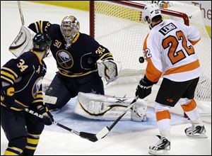 The Flyers’ Ville Leino (22) shakes off pressure from the Sabres’ Chris Butler (34) to score the game-winning goal against Buffalo goalie Ryan Miller in overtime. Leino’s goal was the Flyers’ first lead.