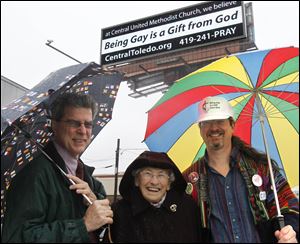 Rev. Bill Barnard, left, Oretha Lawson, and Dan Rutt gather under the billboard. Ms. Lawson, a longtime church member, supports the message. Mr. Rutt is a member of the church’s lead team.
