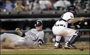 Seattle Mariners' Michael Saunders, left, scores as Detroit Tigers catcher Alex Avila receives the throw on an Ichiro Suzuki single in the ninth inning.