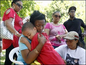 Robin Copeland, center, embraces her grandson Karmello Jones while she sits on the corner of Russell and Mulberry Streets where her son, Deshaun Lee, 16, was shot and killed in this May 29, 2010, file photo. 