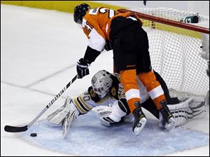 Philadelphia's James van Riemsdyk (21) tumbles over Bruins goalie Tim Thomas (30) during the second period.