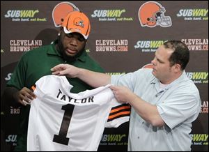 Browns general manager Tom Heckert, right, presents a jersey to first round-draft pick Phillip Taylor during an NFL football news confernce at the team's headquarters in Berea, Ohio on Friday.
