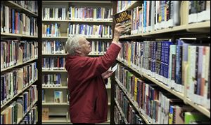 Jean Bertsch looks for books at the Birchard Public Library in Fremont. The library, which has branches in Woodville, Gibsonburg, and Green Springs, is seeking its first operating levy on Tuesday.