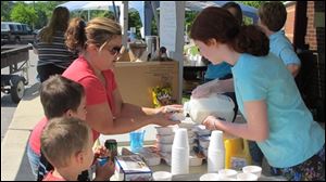 Meaghan Gano, right, a Seventh Day Adventist volunteer, pours milk on a cereal breakfast held by Tricia Greek, for 7-year-old Triston Woods and 5-year-old Troy Woods on Saturday at the elementary school in the storm-ravaged Apison community near Chattanooga, Tenn. 