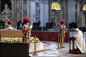 Pope Benedict XVI, right, kneels in prayer in front of the casket of late Pope John Paul II, laid out in state at the Altar of the Confession inside St. Peter's Basilica.