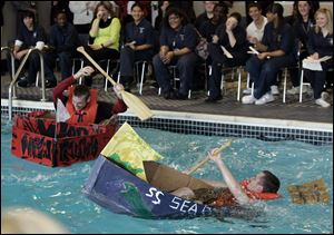 Pilots Joel Snyder, left, and Austin Mattimore attempt to stay afloat during the annual Great Cardboard Boat Race at the Maritime Academy in Toledo. Snyder won the race.