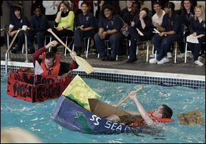 Pilots Joel Snyder, left, and Austin Mattimore attempt to stay afloat during the annual Great Cardboard Boat Race at the Maritime Academy in Toledo. Snyder won the race.