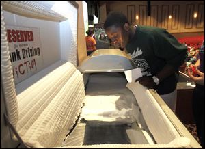 Kabwe Chilupe looks into a casket with a mirror reflecting him, the shock-value part of a message to be safe while driving during prom season.