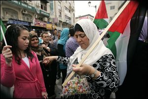A Palestinian woman hands out candy Wednesday during a rally in Ramallah.