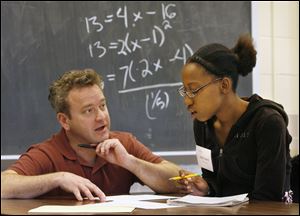 Chad Greeley, an instructor with the Penta Career Center Adult Basic Literacy and Education program, helps Jasmine Coleman, 22, who is working on her GED, in a classroom the program uses at Pickett Academy. Officials hope children seeing the adults taking the classes will have a positive side effect.