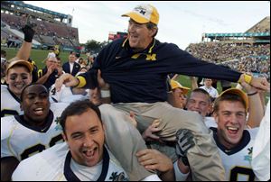 Michigan players carry off their head coach Lloyd Carr off the field after winning the Capital One Bowl in 2008.