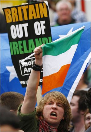 An anti-British protestor waves an Irish tricolor during a demonstration Tuesday near the Garden of Remembrance in Dublin, where Britain's Queen Elizabeth II and Irish President Mary McAleese laid wreaths.