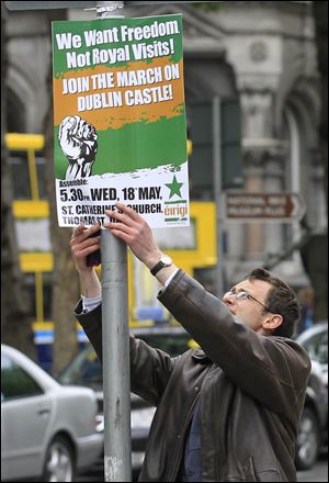 A man puts up a placard to advertise a protest march to coincide with the visit by Britain's Queen Elizabeth II to Ireland.