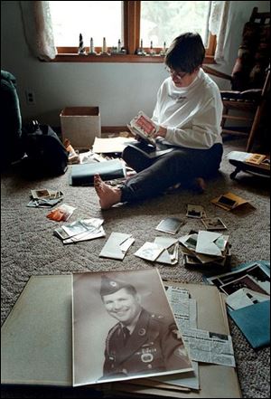 Karen Bruner of Colon, Mich., examines photos of her late husband, who died in 1997. 