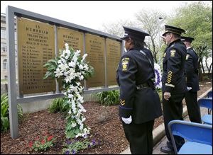 Toledo Police Officer Burna Guy, left, Chief Mike Navarre, and Lt. Sean Jones salute after placing a wreath in the Toledo Police Memorial Garden during the annual Toledo-Area Police Memorial Service.