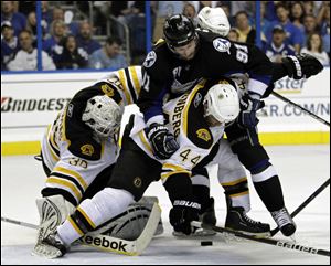 Tampa Bay Lightning's Steven Stamkos (91) gets tangled up with Boston Bruins' Tim Thomas, left, and Dennis Seidenberg (44) while trying to get position on the puck during the second period.