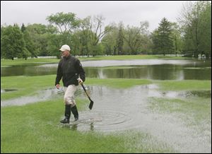 Matt Hudson of Point Place works Thursday to clear drains on the flooded 12th hole of the Toledo Country Club golf course in south Toledo.