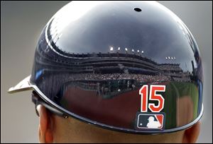 Fulls stands at Progressive Field are reflected in the batting helmet of Cleveland Indians first base coach Sandy Alomar Jr. during a game against the Cincinnati Reds at the Cleveland stadium.