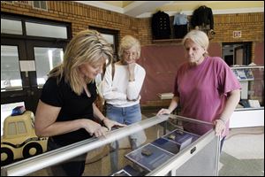 Brenda Miscannon Rollins, left, visiting from Houston, her mother, Jeanette Hurst, center, and sister Diane Miscannon look at an exhibit at the Toledo Police Museum before it opens to the public. They are the daughters and former wife of Officer William Miscannon, who was killed in the line of duty in 1970.