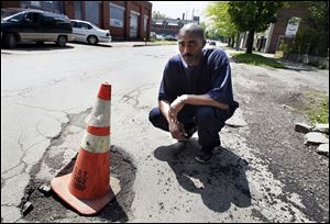 Damon McCullough recently placed an orange cone in a large pothole on West Delaware Avenue in Toledo. Mr. McCullough, who lives on the street, said he has complained to the city about its condition.
