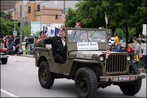 Members of the Zenobia Shrine’s legion of honor ride in a Toledo-built Jeep during the parade that wound through streets of downtown.