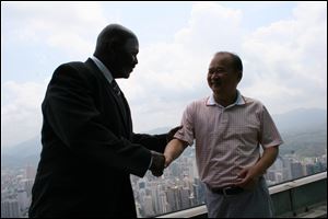 Mayor Mike Bell and Wu King Hung shake hands atop the Empire Building in Shenzhen, Mr. Bell’s first stop. Mr. Wu had a key role in developing the 69-story glass building that soars above the city.