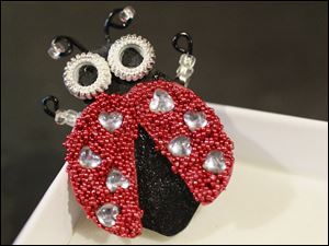 Gourd shells, rhinestones, and microbeads are used to craft a lady bug pin. The pins retail for $10. 