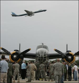 A modern jet plane flies over a WWII bomber during the WWII Stage Door Canteen event.