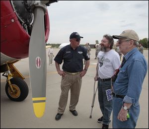 Kevin Donovan shows off a WWII Navy Advance Trainer to Bill Smith, center, and his father, William Smith, an Army vet who recently went on an honor flight, during the WWII Stage Door Canteen event inside the hangar at the 180th Fighter Wing in Swanton, Ohio.