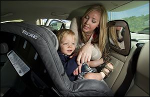 Sarah McIntosh, of Kansas City, North, buckles Ethan McIntosh, 13 months, into his car seat. Sarah uses a stuffed dog with a 
