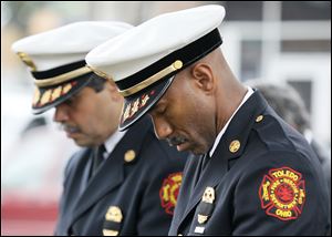 Assistant Fire Chief Luis Santiago, left, and Deputy Chief Brian Byrd bow their heads during the Toledo Fire Department’s annual memorial service for fallen comrades at Chub DeWolfe Park downtown.