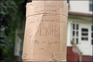 A cardboard memorial tribute is tacked to a pole near where Montelle Taylor was shot.