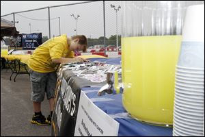 Logan Cook, 10, of Perrysburg signs in at the Locomotive Engineers & Trainmen, Division 385, table, a link in what organizers hope tops 2,571.5 feet, the current record. Fifty-five tables were used to form the lemonade stand.