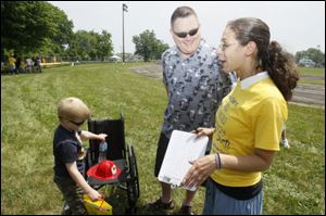 Connor Bell, 6, and his dad, Dave, talk with Inside Angles employee Amber Wilkie, right. Connor, who has osteosarcoma, a cancerous bone tumor, was the inspiration for the lengthy lemonade stand.