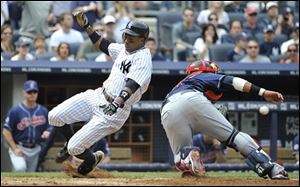 The Yankees' Curtis Granderson beats the throw to Indians catcher Carlos Santana to score on a two run double by Alex Rodriguez in the fifth inning.