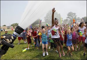 Students at Manor School in Monroe, Mich., including Shania Pippens, 7, jumping, cool off in the spray from a Monroe Fire Department hose.