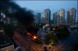 Smoke plumes rise from police cars set on fire Wednesday in Vancouver, British Columbia, following the Vancouver Canucks being defeated by the Boston Bruins in the NHL Stanley Cup final.