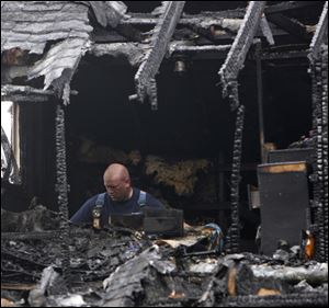 A firefighter sifts through the remains of an early morning house fire in Warren, Ohio, that killed six people Thursday.