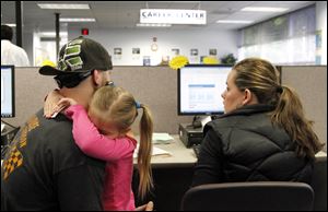 Matthew Weisker holds his daughter, Lexi, 4, as he and his wife, Mindy, seek jobs in the Worksource Oregon database in Tualatin, Ore. 