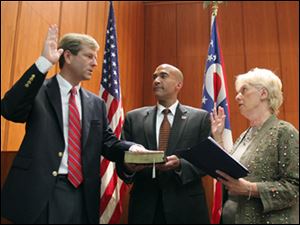 Jon Stainbrook swears his oath of office to Ohio Supreme Court Justice Judith Lanzinger on a Bible held by her son, Josh Lanzinger. 