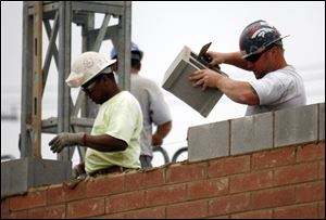 Masonry workers lay bricks on a new building that will be in a Fremont Pike strip mall.
