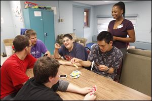 Life coach Ed Bollinger, at the table’s head, and assistant director Tasha Buck, standing, watch as, from left, Jared Urman, Dustin Bahrs, Nick Morningstar, and Jeremy Lee play UNO at the Self Reliance Center.