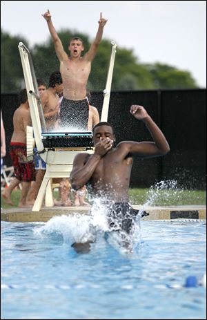 William Anderson, 18, jumps into the pool while Anthony LaCourse, 18, cheers him on at Rolf Park, in Maumee Tuesday.