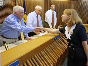 Anne Baker, right, executive director of the Toledo Zoo, shakes hands with Wood County Commissioner Alvin Perkins as commissioners James Carter, center left, and Tim Brown look on Tuesday.