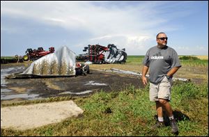 Willie van der Merwe surveys the damage Monday after a tornado destroyed a building housing farm machinery at Triple C Farms, located about 5 miles west of Long Island, Kan., where van der Merwe works.