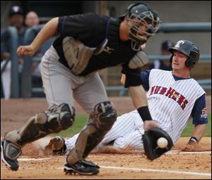The Mud Hens' Ryan Strieby slides in safely while Louisville catcher Devin Mesoraco fields the ball.