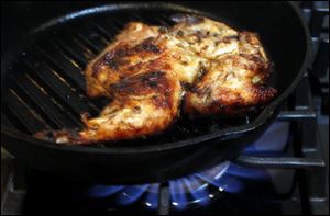 Chicken cooks in a grill pan.