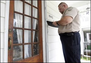 Officer Gene Boros, an animal cruelty investigator with the Toledo Humane Society, waits for a response at a Toledo home to which he was dispatched.