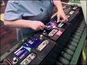 A worker puts labels on batteries at Johnson Controls in this file photo.